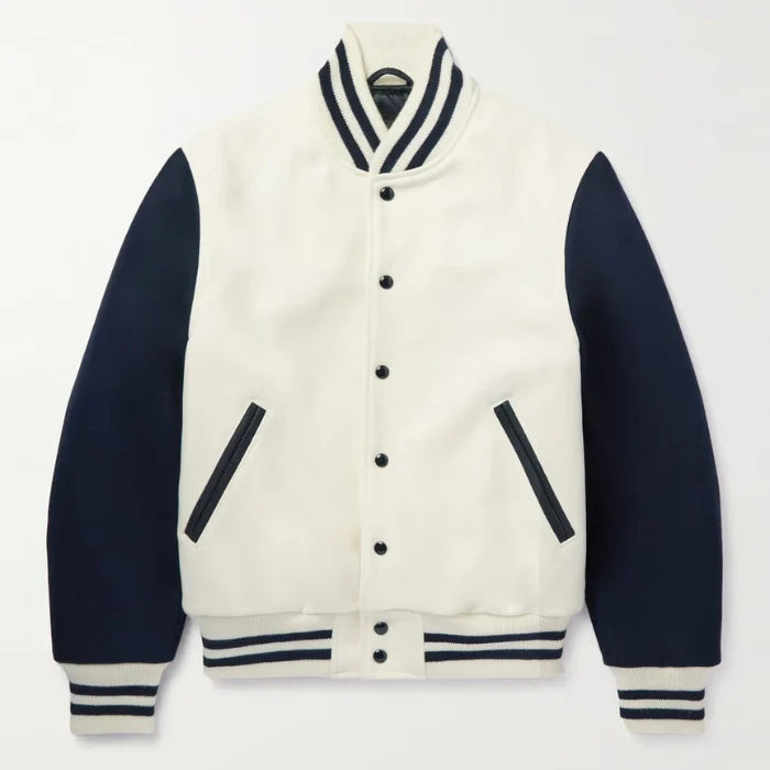 Person wearing a white and navy varsity jacket over a striped shirt on a plain background