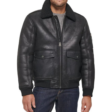 Front view of model wearing black aviator leather bomber jacket with a plush shearling-lined collar, silver-toned zippers, and black buttons.