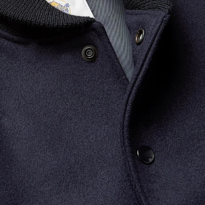 Navy blue varsity jacket with buttons on a dark background